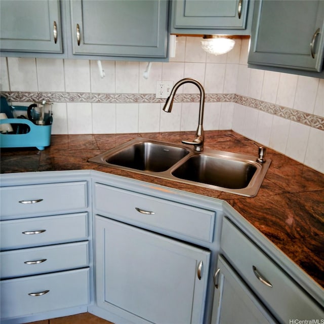 kitchen with dark countertops, a sink, and tasteful backsplash