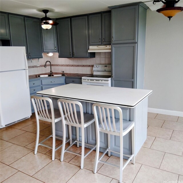 kitchen featuring a sink, under cabinet range hood, white appliances, and light tile patterned flooring