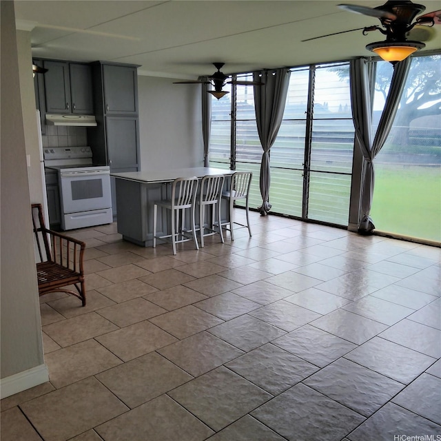 kitchen featuring white range with electric cooktop, light countertops, floor to ceiling windows, under cabinet range hood, and a ceiling fan