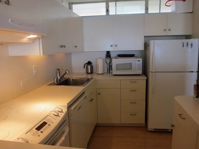 kitchen with a sink, white appliances, light countertops, white cabinets, and wood finished floors