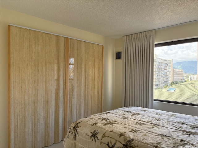 2140 Kuhio Ave Unit 911, Honolulu, HI 96815 - bedroom with visible vents, a textured ceiling, and a mountain view