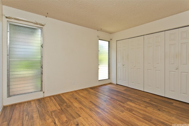 unfurnished bedroom with a textured ceiling, a closet, and wood finished floors