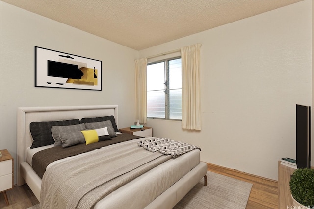 bedroom with a textured ceiling and wood finished floors
