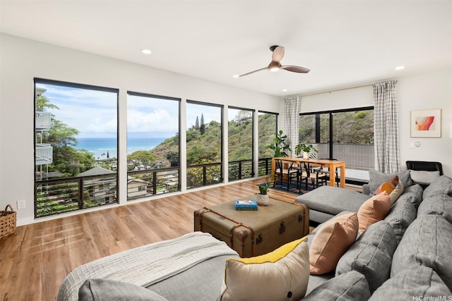 living room featuring recessed lighting, wood finished floors, ceiling fan, and a water view