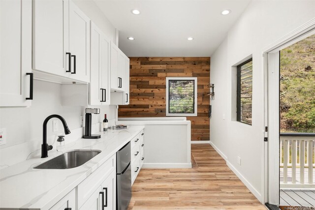 kitchen featuring recessed lighting, light stone counters, light wood finished floors, a sink, and white cabinetry