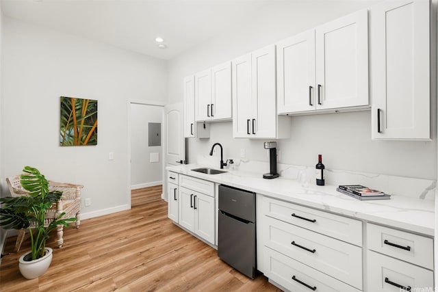 kitchen featuring fridge, white cabinets, a sink, baseboards, and light wood-type flooring