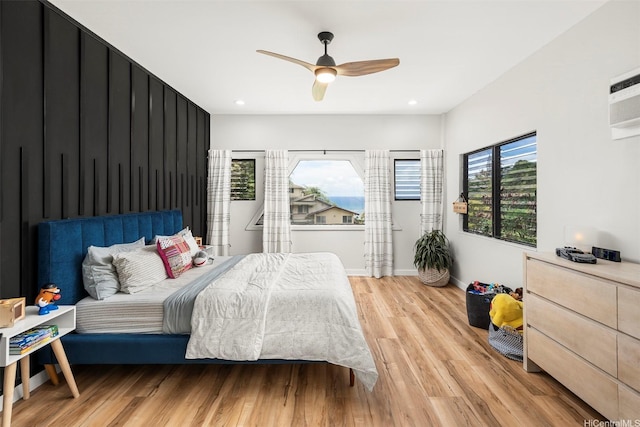 bedroom featuring recessed lighting, light wood-style floors, a wall mounted AC, baseboards, and a ceiling fan
