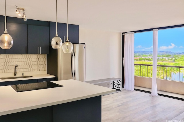 320 Liliuokalani Ave Unit 902, Honolulu, HI 96815 - kitchen featuring black electric stovetop, freestanding refrigerator, decorative light fixtures, backsplash, and light countertops