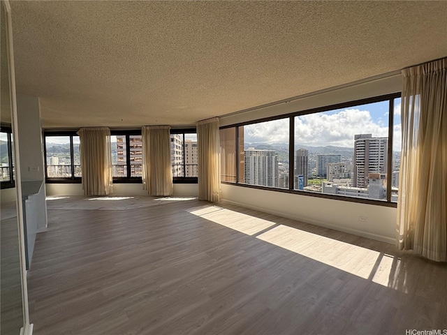1778 Ala Moana Blvd Unit 3616, Honolulu, HI 96815 - spare room featuring a textured ceiling, wood finished floors, a city view, and baseboards