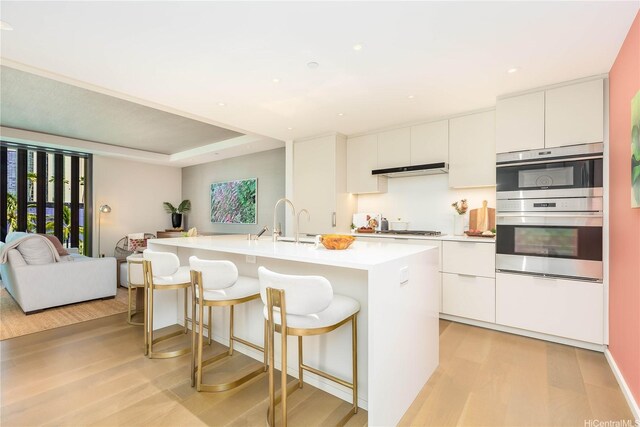 1388 Ala Moana Blvd Unit 1405, Honolulu, HI 96814 - kitchen featuring light wood-type flooring, a kitchen island with sink, modern cabinets, stainless steel appliances, and light countertops