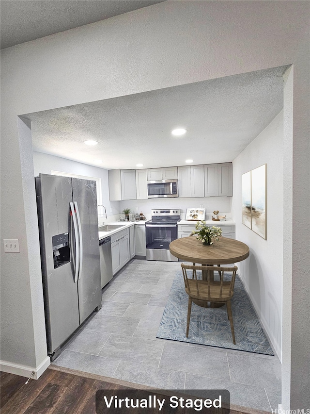 91-444 Pohakupuna Rd, Ewa Beach, HI 96706 - kitchen with a textured ceiling, gray cabinetry, light countertops, a sink, and stainless steel appliances