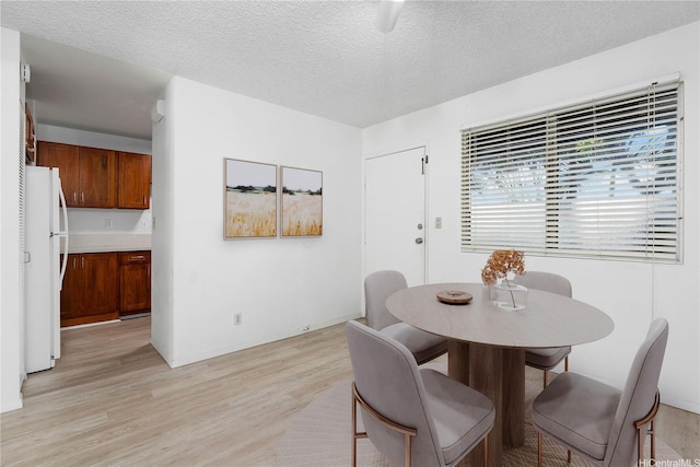 dining space featuring light wood-style flooring and a textured ceiling