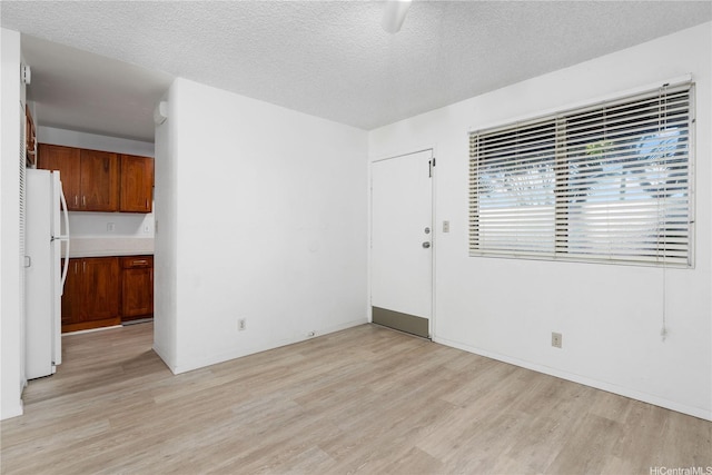 spare room featuring a textured ceiling and light wood finished floors