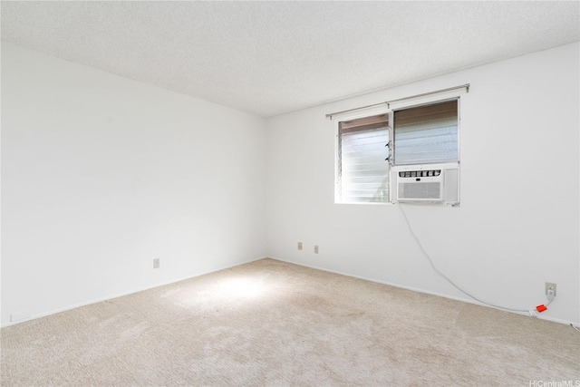 carpeted spare room featuring a textured ceiling, cooling unit, and baseboards