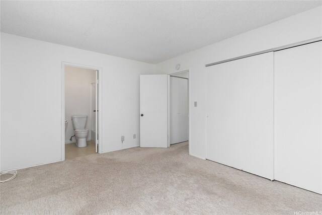 unfurnished bedroom with carpet, ensuite bath, and a closet
