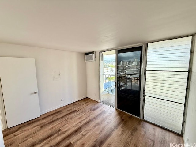 2122 Lime St Unit 604, Honolulu, HI 96826 - unfurnished room with wood finished floors, an AC wall unit, and baseboards