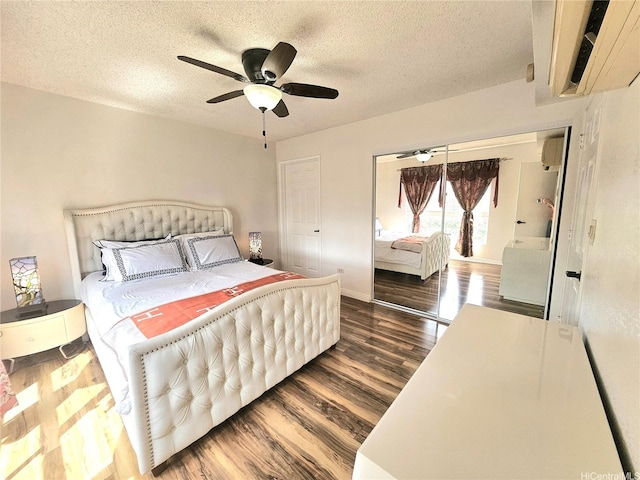 bedroom with a textured ceiling, baseboards, an AC wall unit, wood finished floors, and a ceiling fan