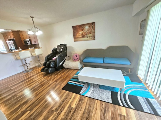 living room with wood finished floors, a chandelier, and baseboards
