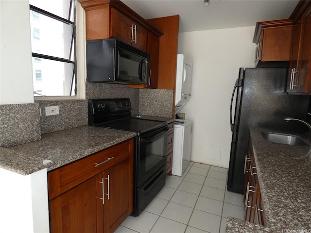 2410 Cleghorn St Unit 502, Honolulu, HI 96815 - kitchen with black appliances, stacked washer / drying machine, tasteful backsplash, light tile patterned floors, and dark stone counters