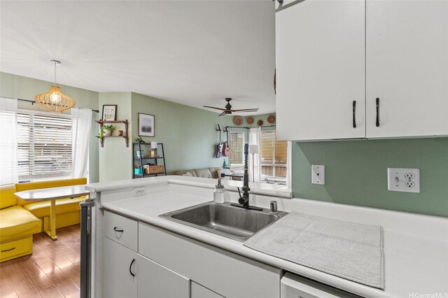 kitchen featuring a sink, ceiling fan, light countertops, and white cabinetry