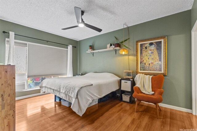 bedroom with wood finished floors, a textured ceiling, baseboards, and ceiling fan
