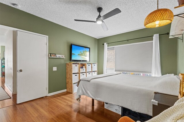 bedroom featuring wood finished floors, a textured ceiling, and a ceiling fan