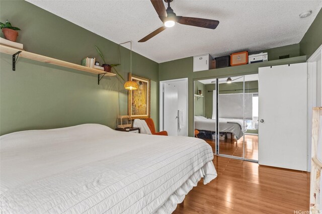 bedroom featuring wood finished floors, a closet, a textured ceiling, and a ceiling fan