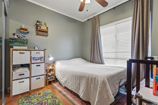 bedroom featuring crown molding, wood finished floors, and a ceiling fan