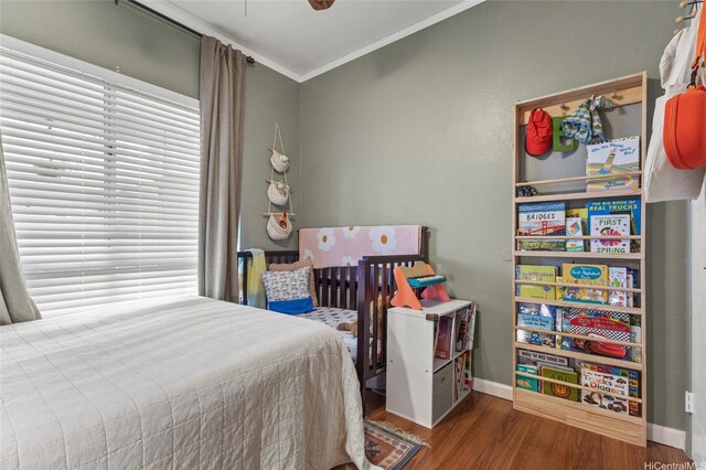 bedroom with crown molding, wood finished floors, and baseboards