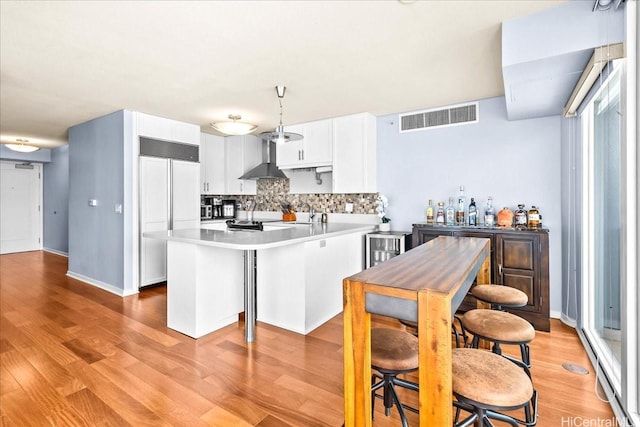 1296 Kapiolani Blvd Unit 3403, Honolulu, HI 96814 - kitchen with built in fridge, a peninsula, wall chimney range hood, decorative backsplash, and light countertops