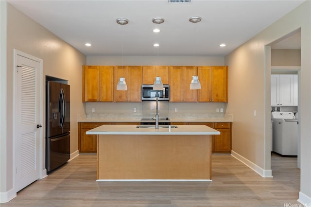 kitchen featuring stainless steel microwave, light wood finished floors, black fridge with ice dispenser, and light countertops