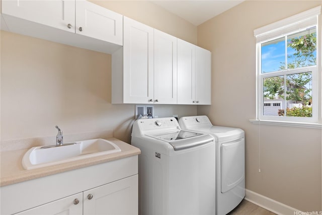 laundry area with a sink, cabinet space, independent washer and dryer, and baseboards