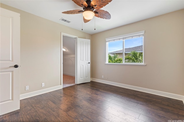 unfurnished bedroom featuring hardwood / wood-style flooring, visible vents, a closet, baseboards, and a walk in closet