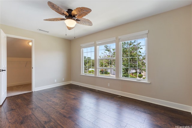 unfurnished room with a ceiling fan, visible vents, dark wood-style flooring, and baseboards