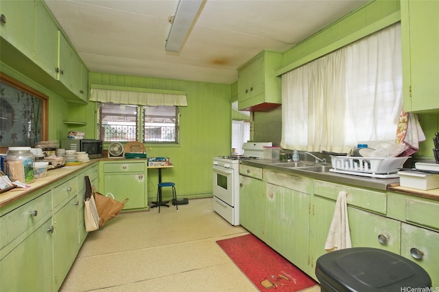kitchen with light countertops, white range with gas cooktop, stainless steel microwave, a sink, and green cabinets
