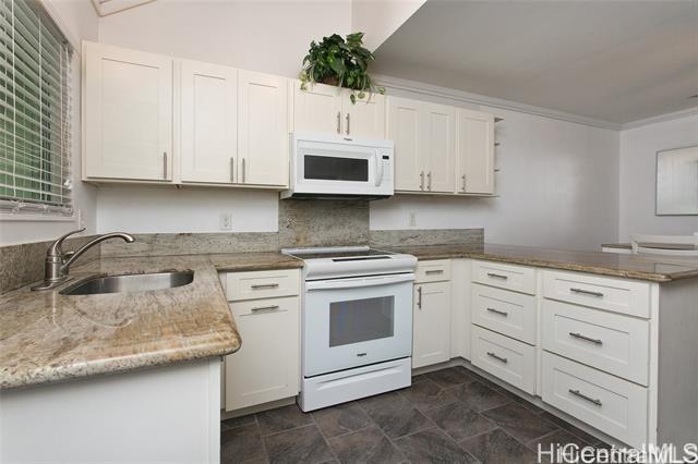 kitchen with white cabinetry, a sink, light stone countertops, white appliances, and a peninsula