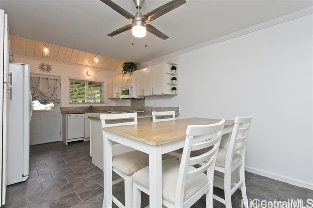 dining room with crown molding, a ceiling fan, stone finish floor, and baseboards