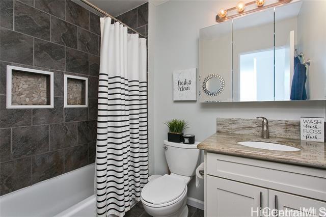 bathroom featuring toilet, shower / bath combo with shower curtain, and vanity