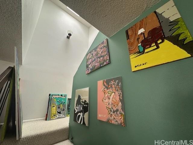 staircase featuring lofted ceiling, carpet, and a textured ceiling