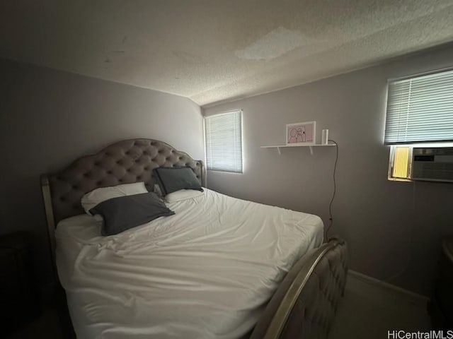 bedroom featuring cooling unit, a textured ceiling, and baseboards