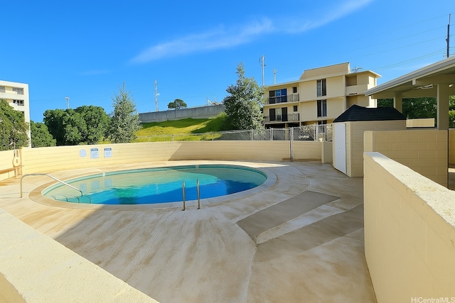 community pool with fence and a patio area