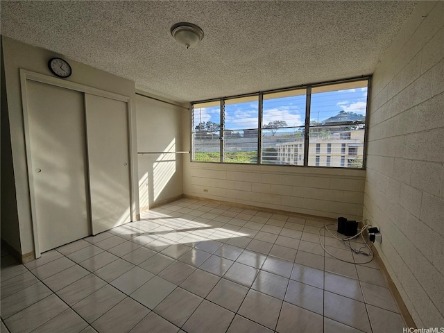 unfurnished bedroom with a textured ceiling, light tile patterned floors, and a closet