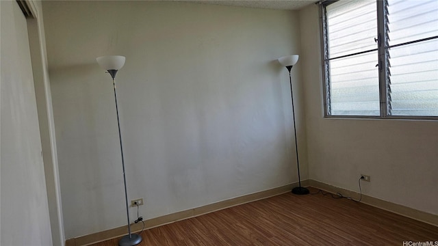empty room featuring baseboards and dark wood-type flooring