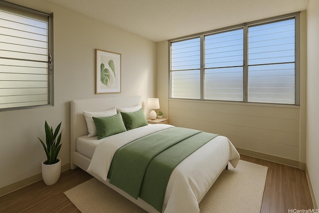 bedroom with multiple windows, wood finished floors, and baseboards