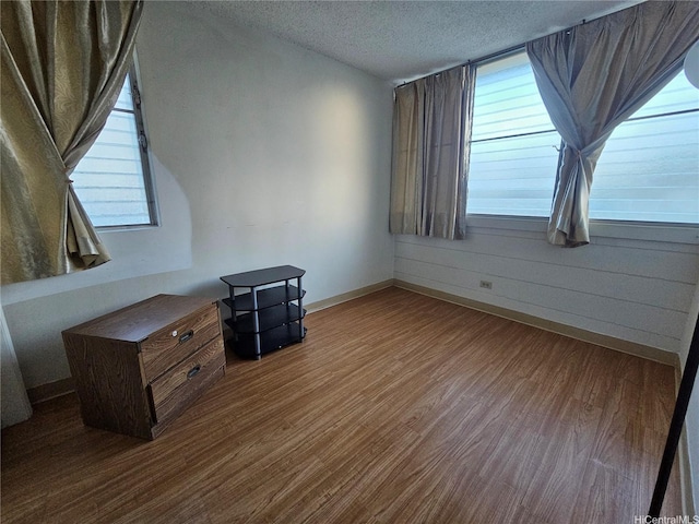 interior space featuring a textured ceiling, wood finished floors, and baseboards