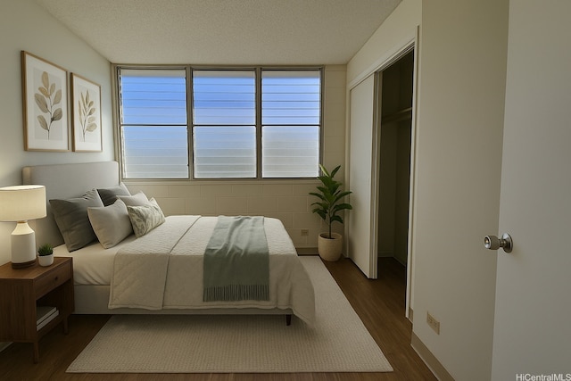 bedroom with a textured ceiling, a closet, and dark wood finished floors