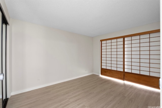 2542 Date St Unit 904, Honolulu, HI 96826 - empty room with baseboards, a textured ceiling, and light wood finished floors