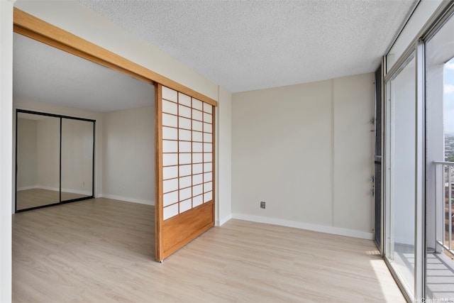 2542 Date St Unit 904, Honolulu, HI 96826 - empty room featuring light wood-type flooring, a textured ceiling, and baseboards