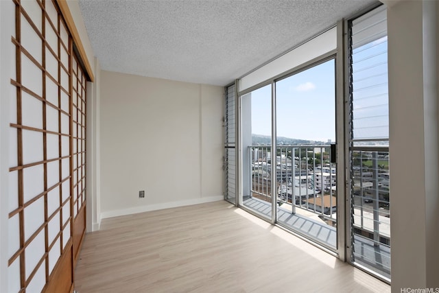 2542 Date St Unit 904, Honolulu, HI 96826 - spare room with baseboards, a textured ceiling, wood finished floors, and a wall of windows