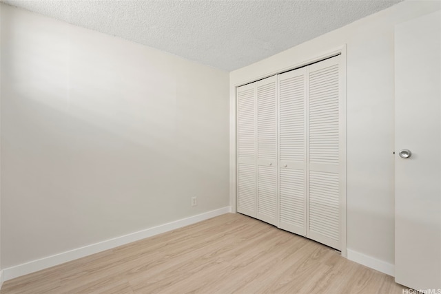 2542 Date St Unit 904, Honolulu, HI 96826 - unfurnished bedroom with a closet, a textured ceiling, baseboards, and light wood-style floors